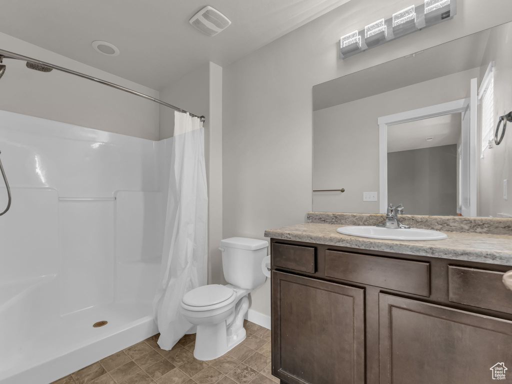 Full bathroom featuring toilet, vanity, curtained shower, and baseboards