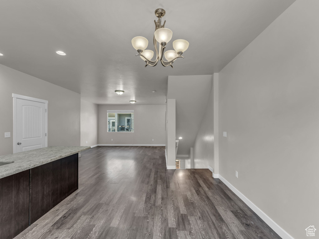 Unfurnished living room with dark wood-style flooring, baseboards, a chandelier, and recessed lighting