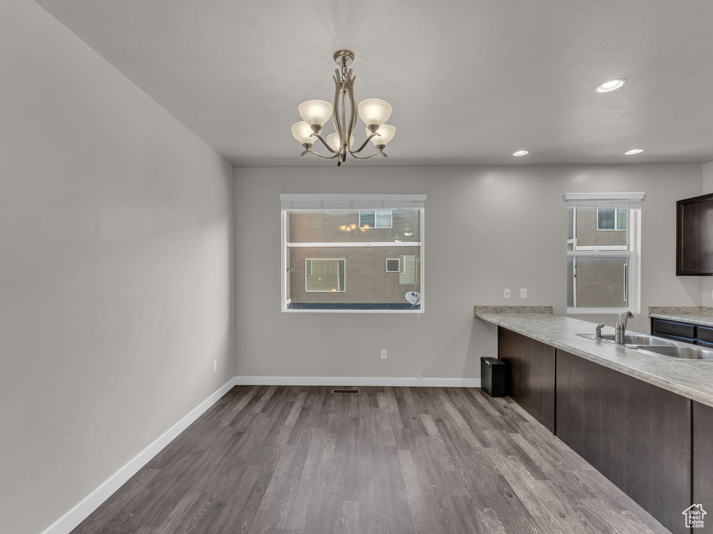 Unfurnished dining area featuring a sink, dark wood-style floors, a chandelier, baseboards, and recessed lighting