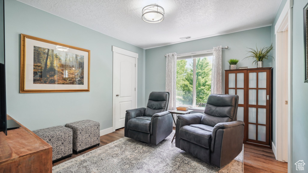 Living area featuring wood finished floors, a textured ceiling, and baseboards