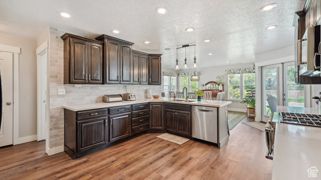 Kitchen with appliances with stainless steel finishes, baseboards, light countertops, light wood finished floors, and a textured ceiling