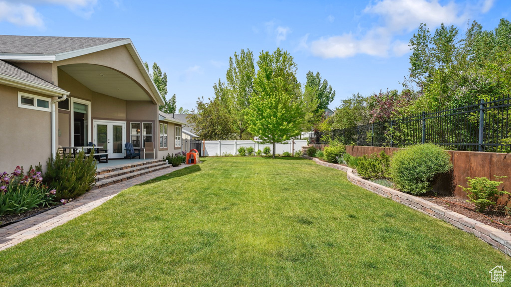 View of yard with french doors and a patio
