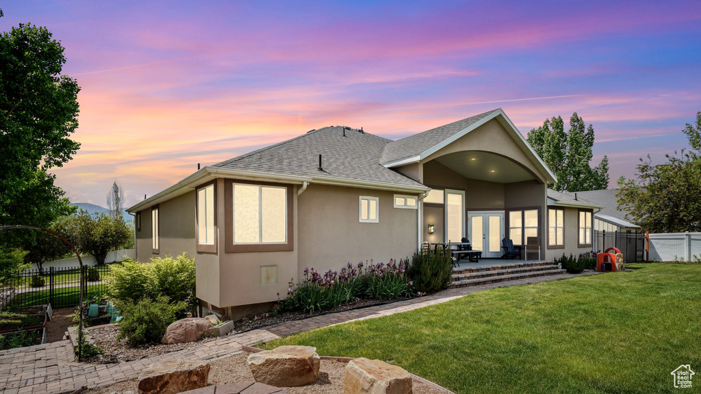 View of front of house with stucco siding, a shingled roof, and a patio