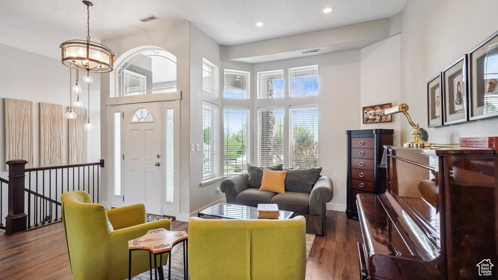 Living room featuring a towering ceiling, wood finished floors, recessed lighting, baseboards, and a chandelier