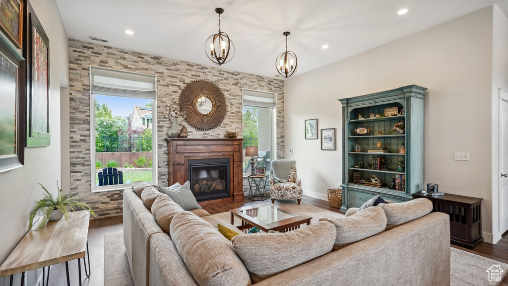 Living area featuring wood finished floors, a glass covered fireplace, recessed lighting, a chandelier, and baseboards