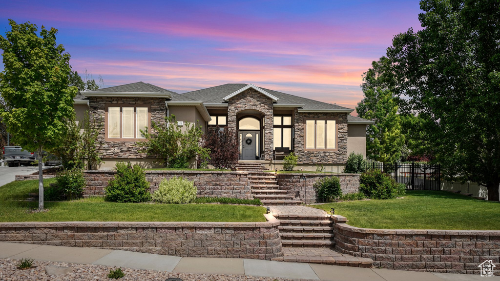 Prairie-style home featuring stucco siding, roof with shingles, and stone siding