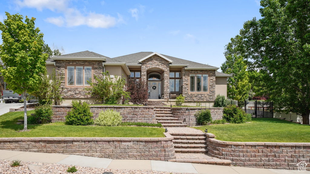Prairie-style house featuring stucco siding, stone siding, and a shingled roof