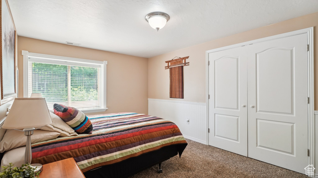 Carpeted bedroom featuring wainscoting