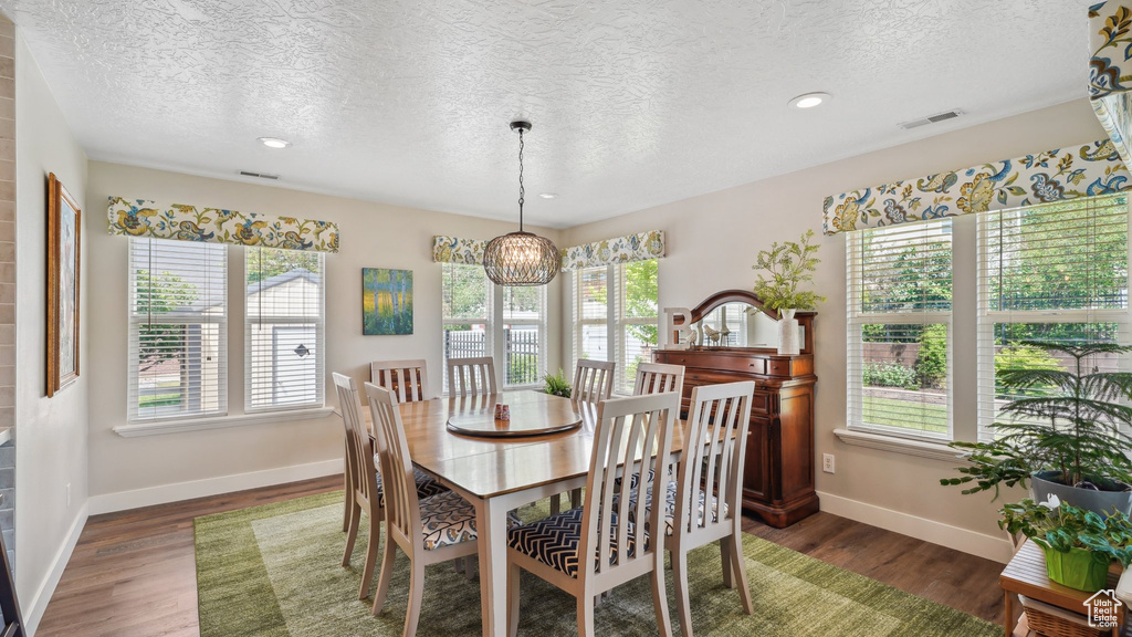 Dining room with a textured ceiling, wood finished floors, baseboards, a chandelier, and recessed lighting