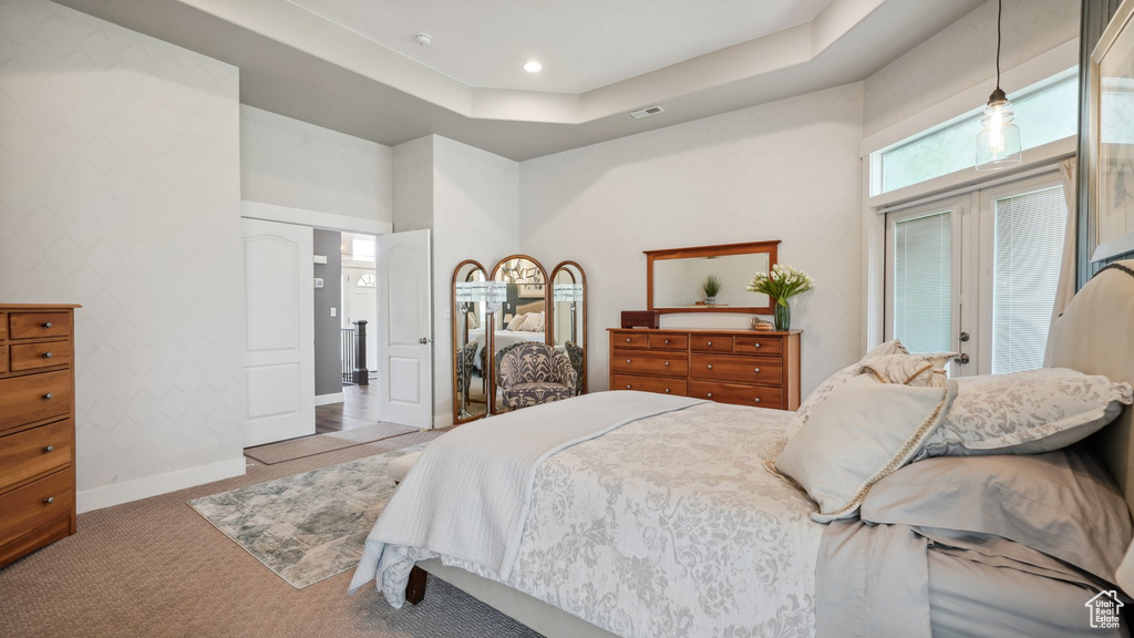 Carpeted bedroom featuring a towering ceiling, baseboards, a tray ceiling, and access to outside
