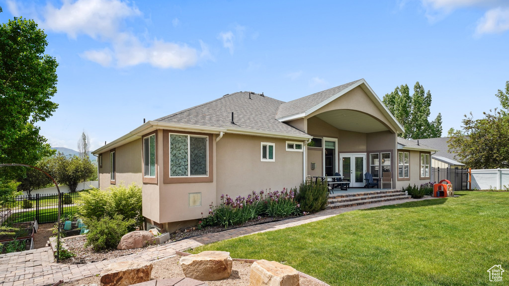 View of front of home with stucco siding, a patio area, french doors, and roof with shingles