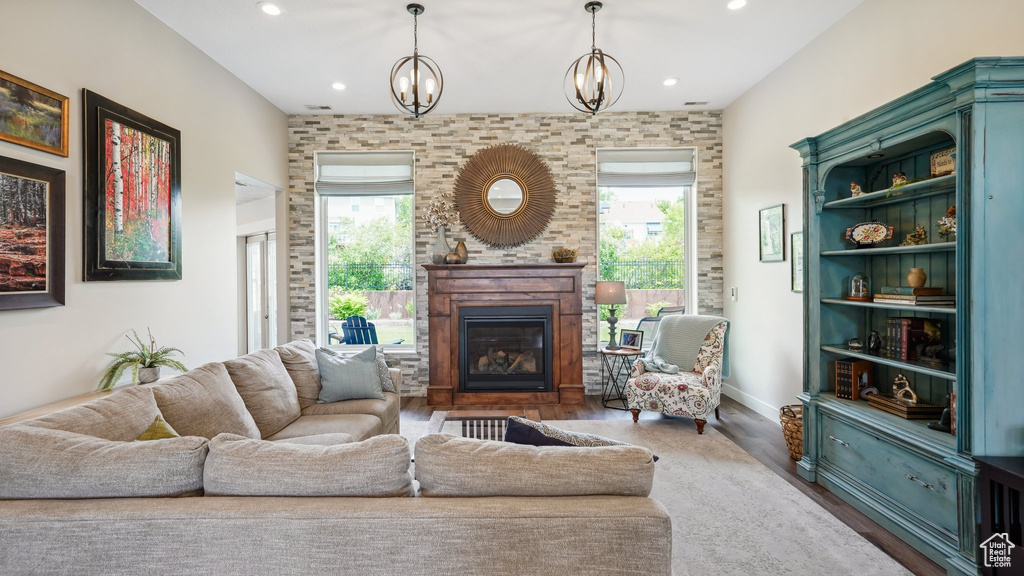 Living room featuring a glass covered fireplace, wood finished floors, recessed lighting, and a chandelier