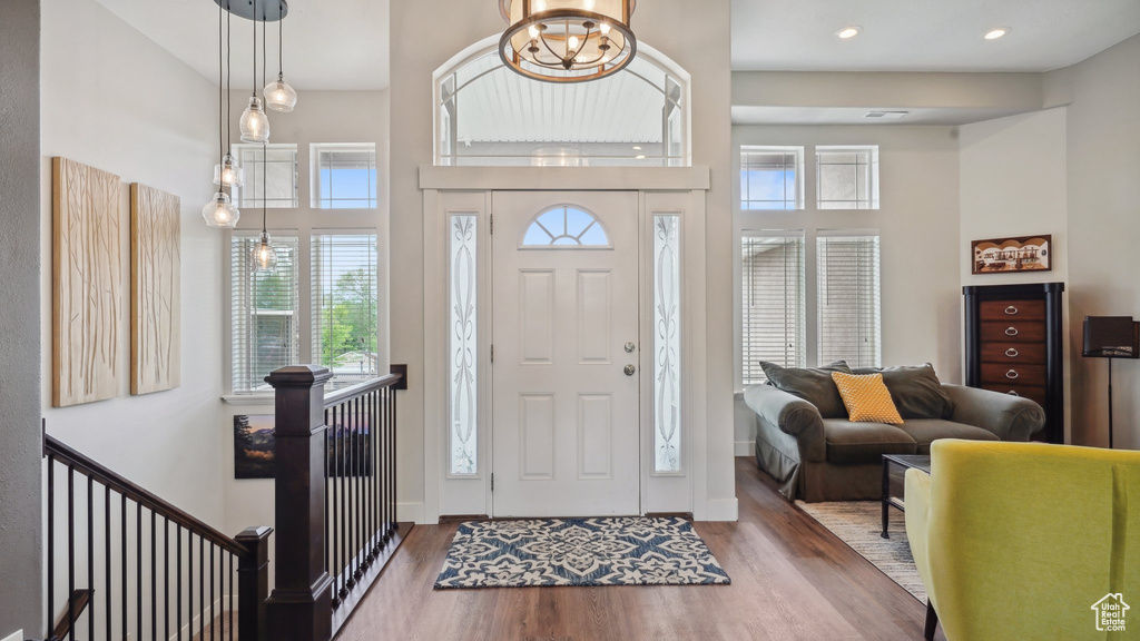 Entryway with wood finished floors, a towering ceiling, baseboards, recessed lighting, and a chandelier