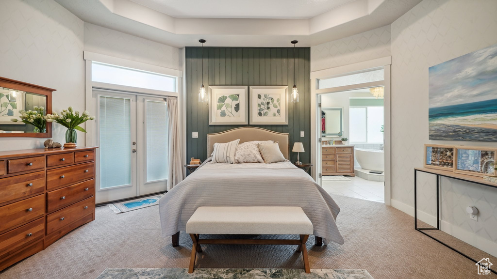 Bedroom with light carpet, multiple windows, access to exterior, connected bathroom, and a towering ceiling
