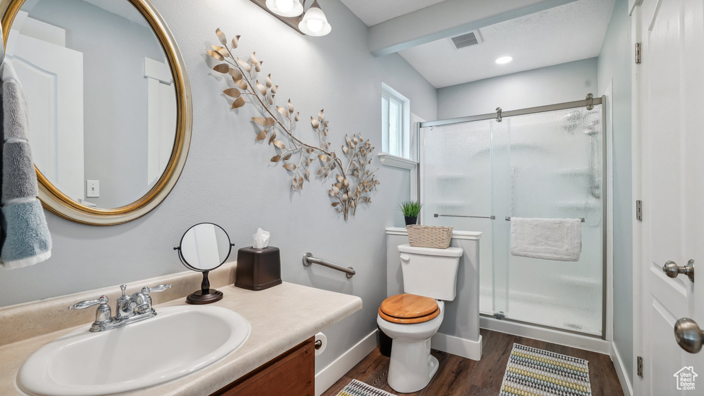 Full bathroom with toilet, a stall shower, vanity, wood finished floors, and baseboards