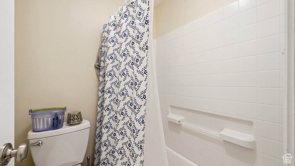Bathroom with toilet and shower / bath combination with curtain