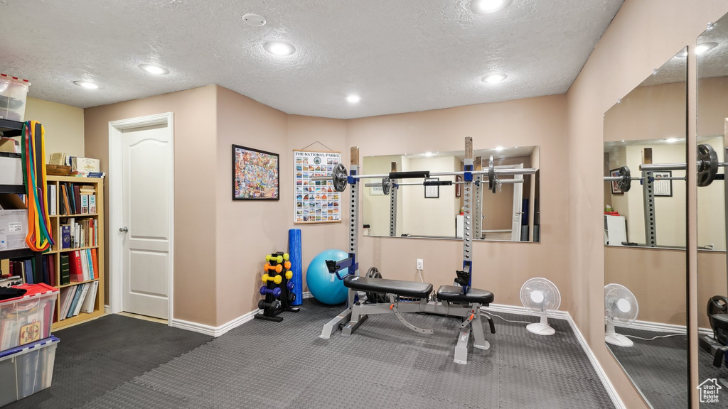 Exercise area with baseboards, a textured ceiling, and recessed lighting