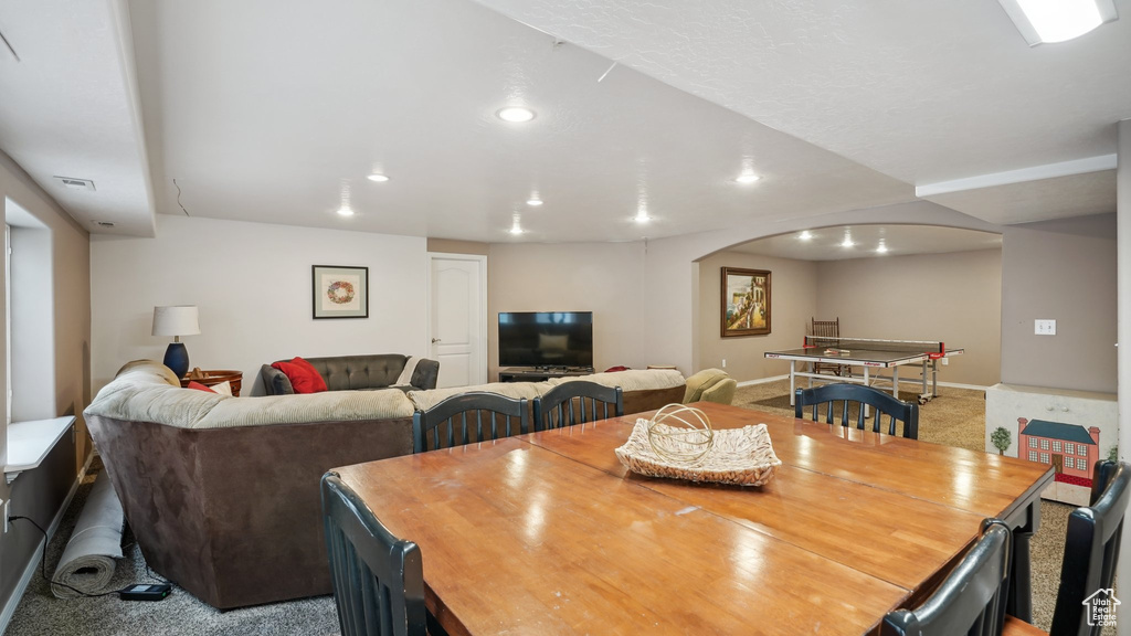Dining area with arched walkways, carpet floors, and recessed lighting