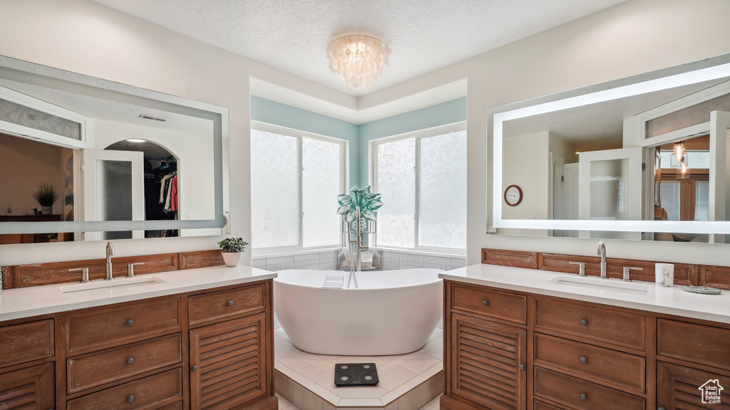 Full bathroom with two vanities, a soaking tub, and a chandelier