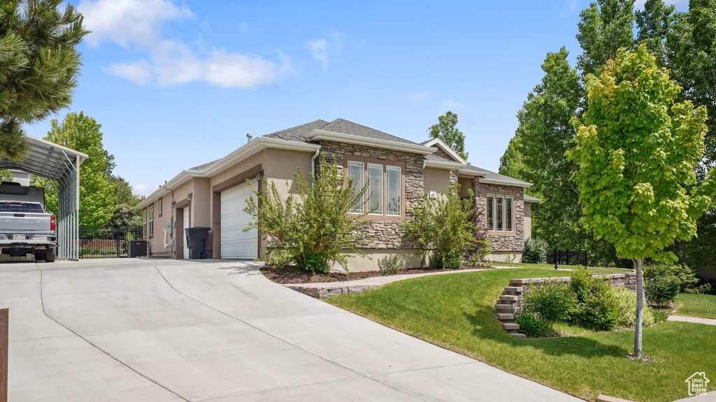 View of front of home featuring a garage, stone siding, driveway, stucco siding, and central air condition unit
