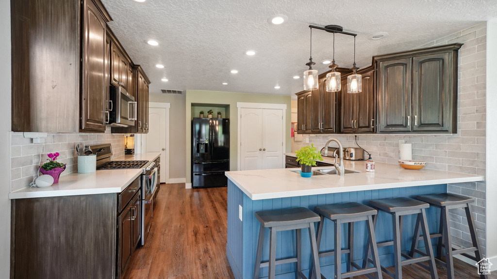Kitchen featuring stainless steel appliances, a peninsula, a sink, tasteful backsplash, and light countertops