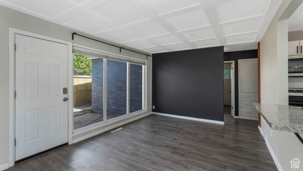 Unfurnished dining area featuring baseboards, dark wood-style flooring, and coffered ceiling