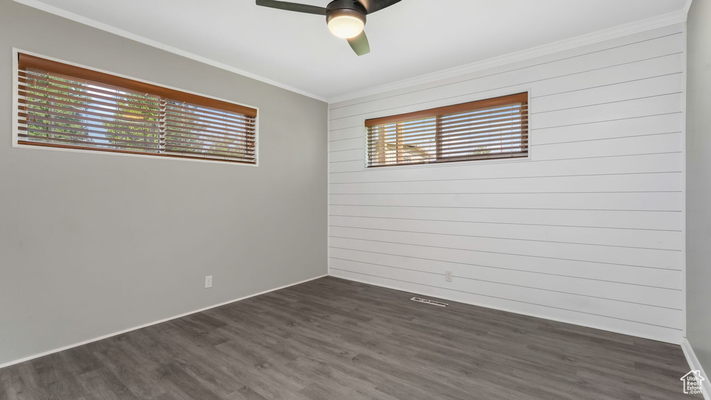 Spare room with ornamental molding, dark wood-style flooring, a ceiling fan, and baseboards