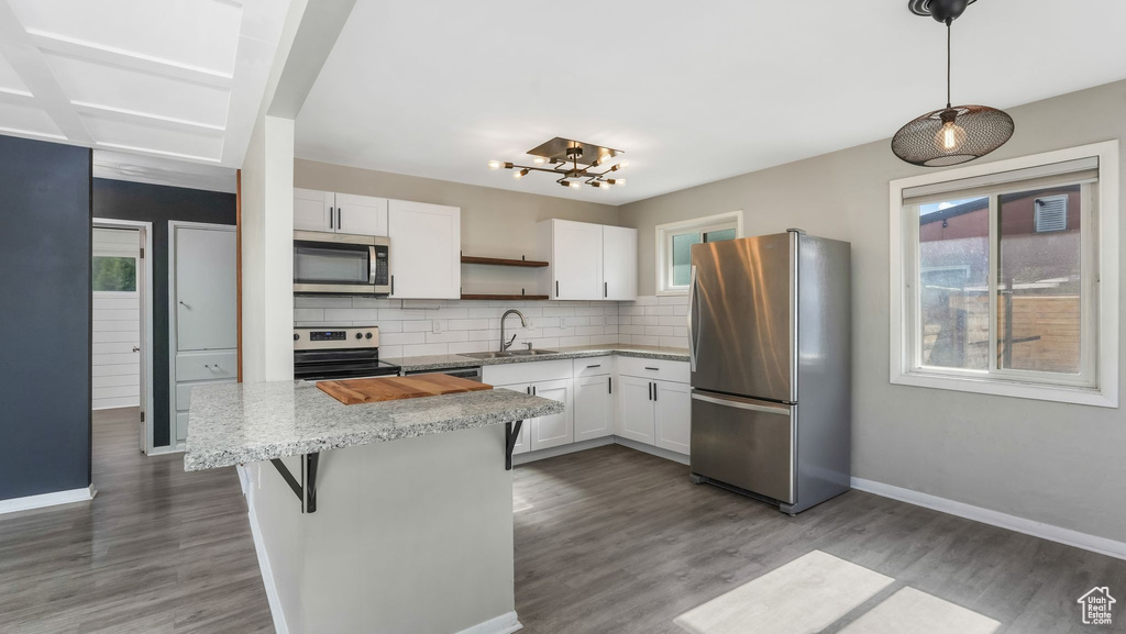 Kitchen featuring appliances with stainless steel finishes, open shelves, white cabinetry, a sink, and backsplash