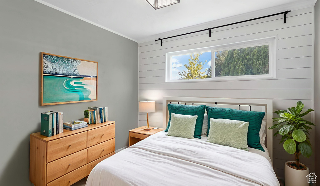 Bedroom with ornamental molding and wood walls