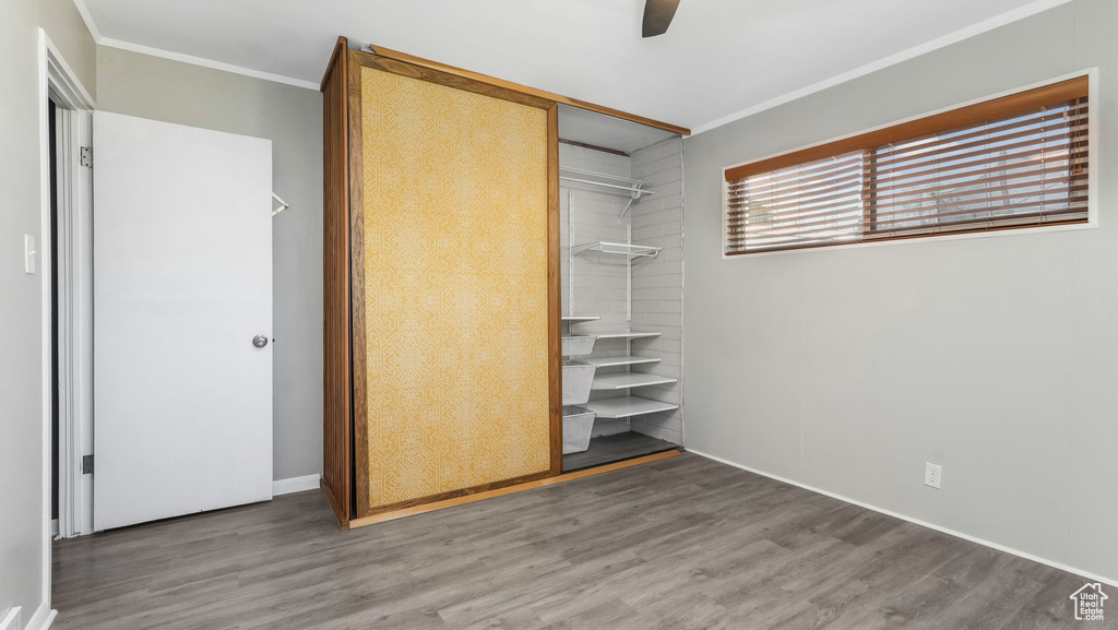 Unfurnished bedroom with ornamental molding, wood finished floors, a closet, baseboards, and ceiling fan