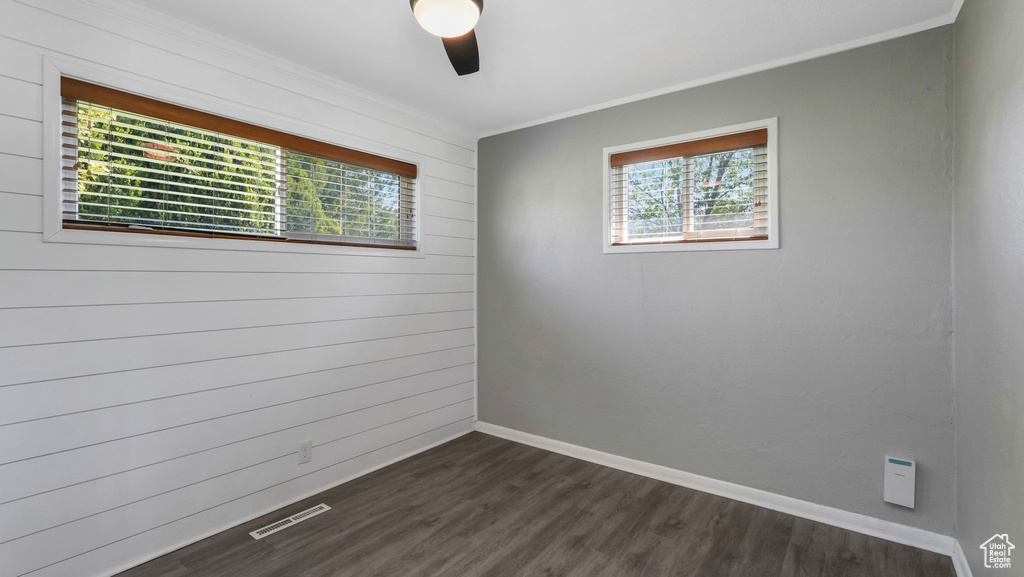 Spare room featuring ceiling fan, dark wood-type flooring, ornamental molding, and baseboards