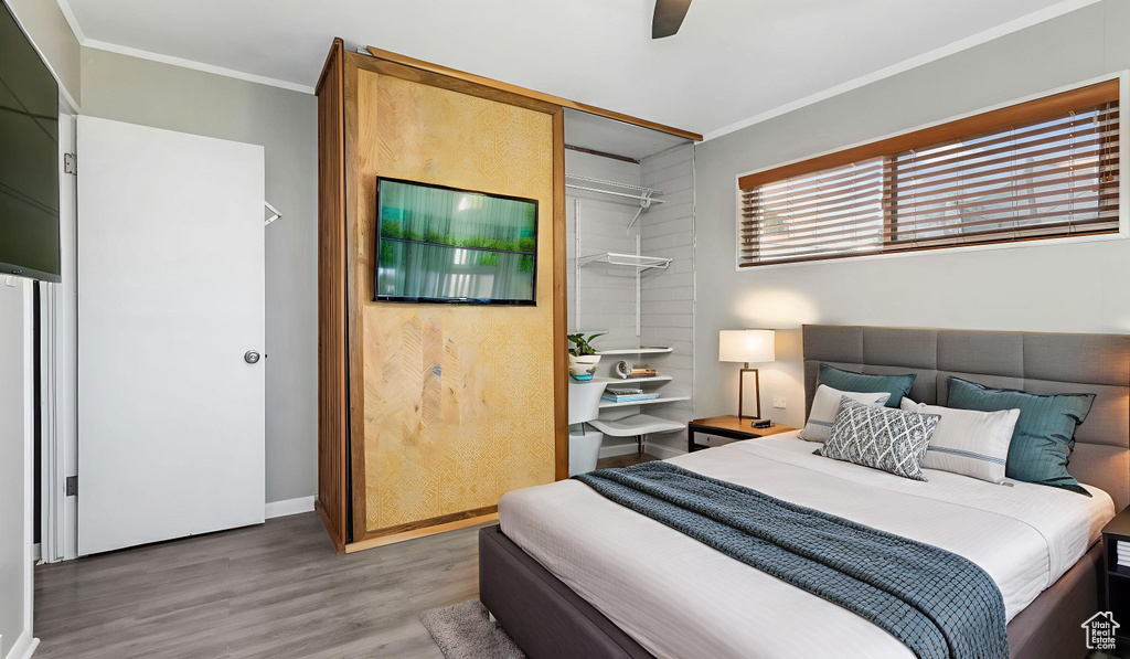 Bedroom with crown molding, light wood-type flooring, a ceiling fan, and baseboards