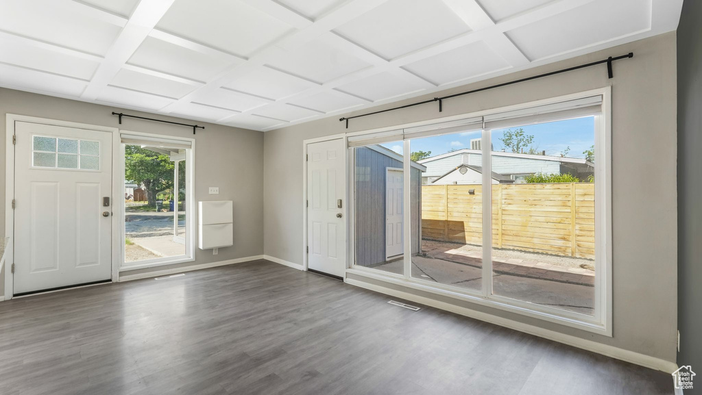 Doorway featuring baseboards, wood finished floors, and coffered ceiling