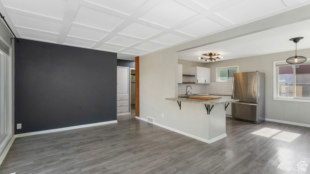 Kitchen with freestanding refrigerator, a sink, coffered ceiling, a peninsula, and white cabinets