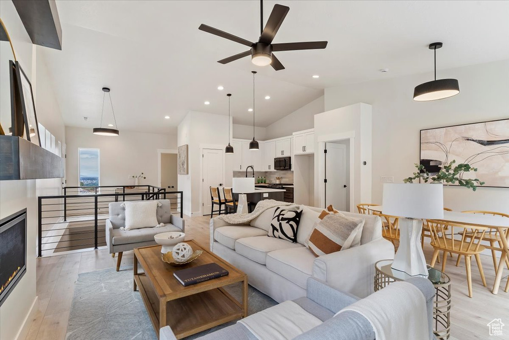 Living room with ceiling fan, light wood finished floors, recessed lighting, and vaulted ceiling
