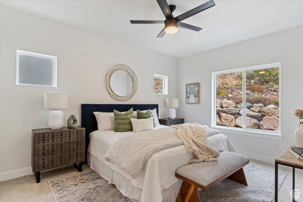 Bedroom with light colored carpet, baseboards, and ceiling fan