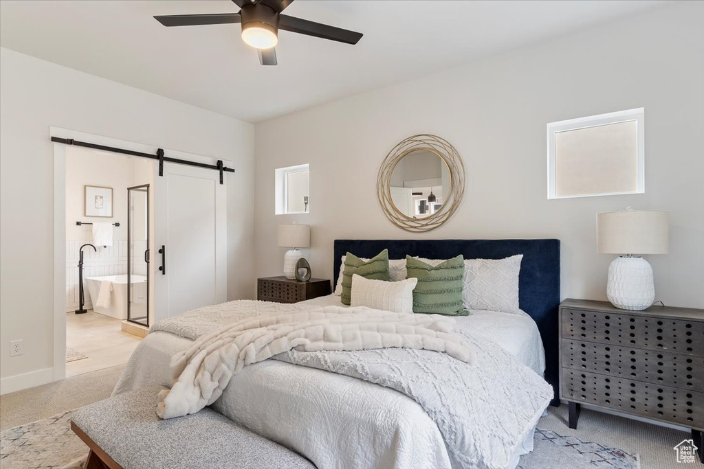 Bedroom with a barn door, carpet floors, a ceiling fan, ensuite bath, and baseboards