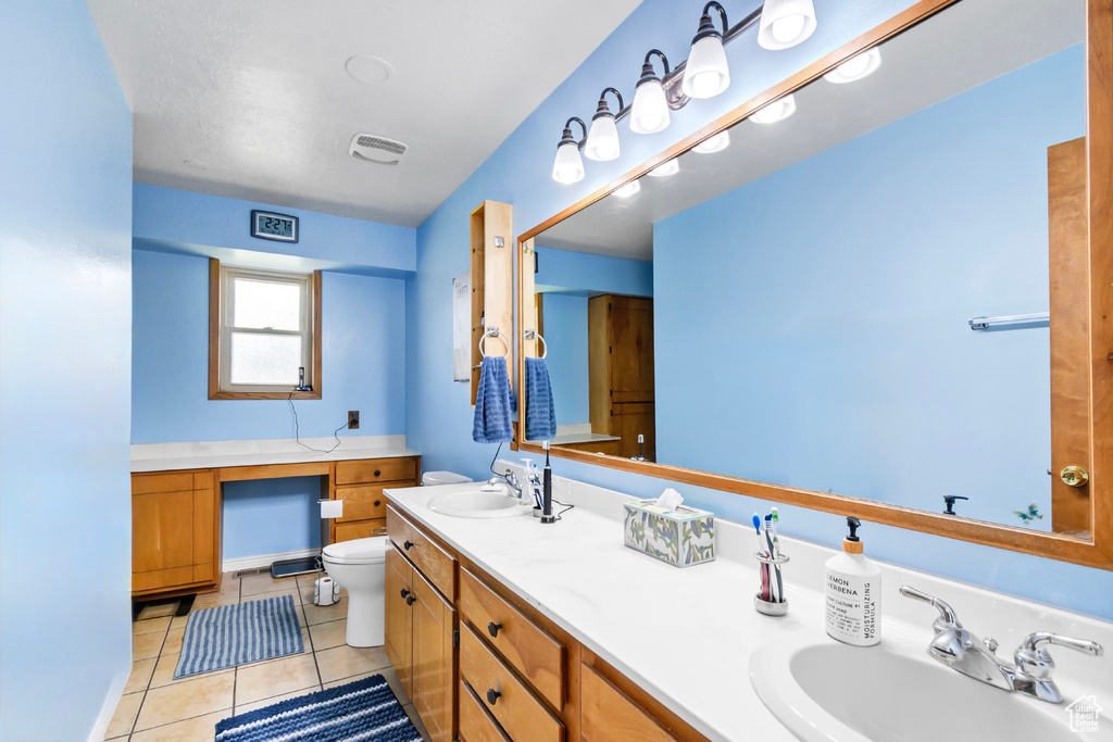 Bathroom featuring toilet, double vanity, and tile patterned floors