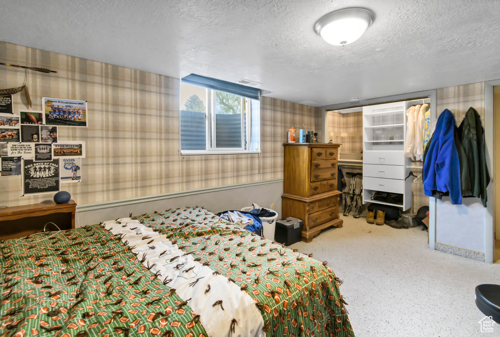 Bedroom featuring wallpapered walls and a textured ceiling