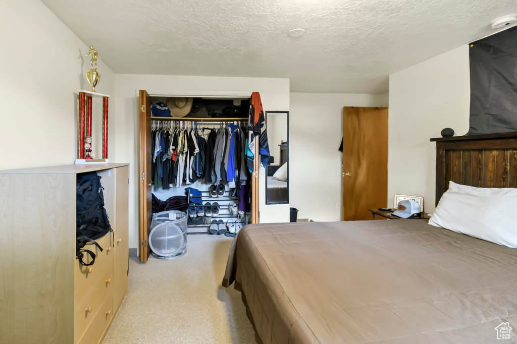 Carpeted bedroom featuring a closet and a textured ceiling