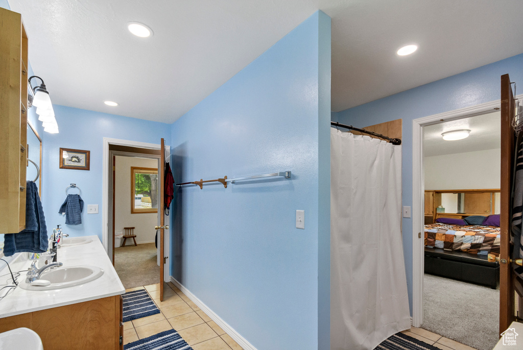 Ensuite bathroom featuring tile patterned floors, double vanity, recessed lighting, a shower with curtain, and baseboards