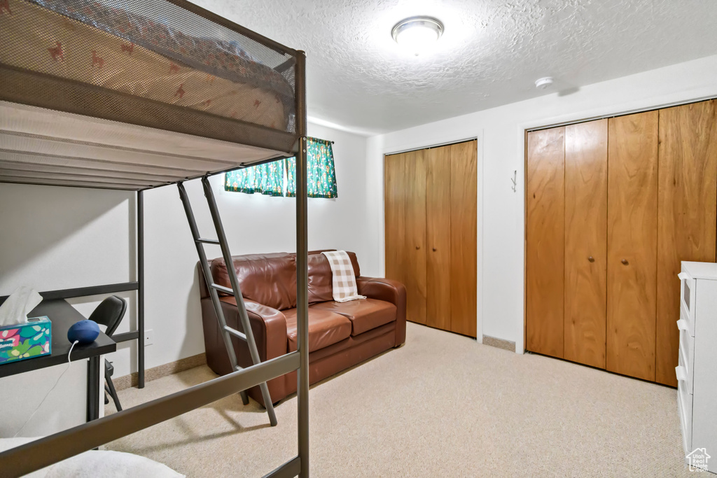 Bedroom with two closets, a textured ceiling, and carpet floors