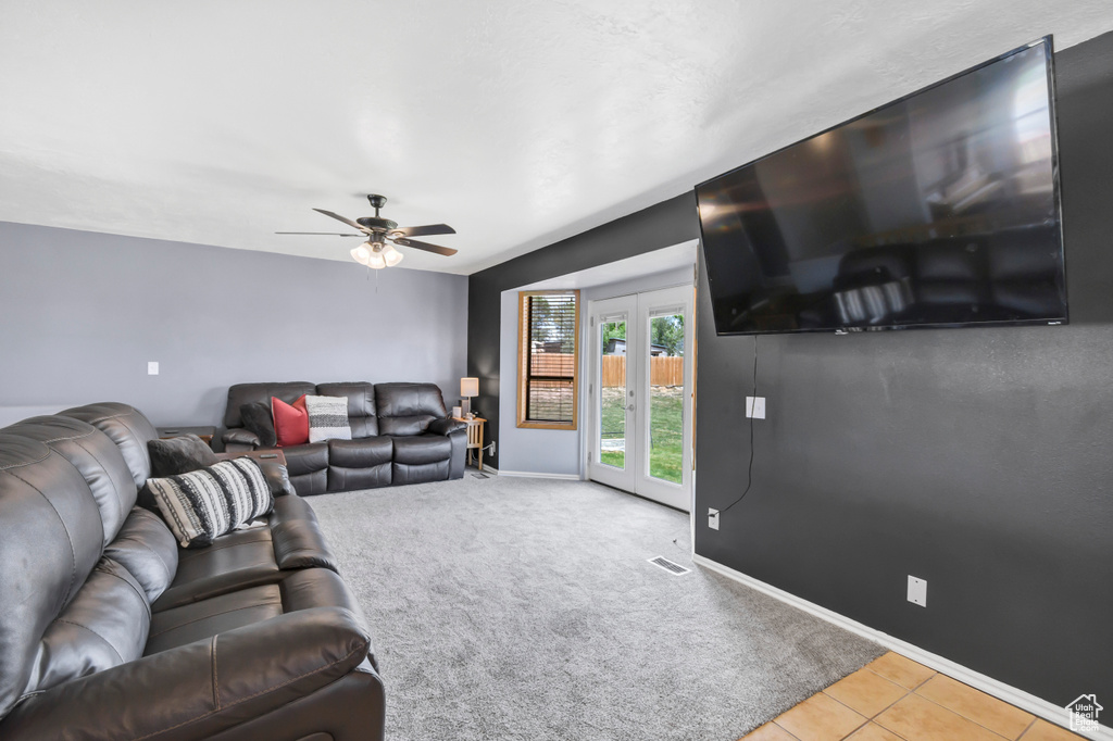 Carpeted living room with french doors, ceiling fan, baseboards, and tile patterned flooring
