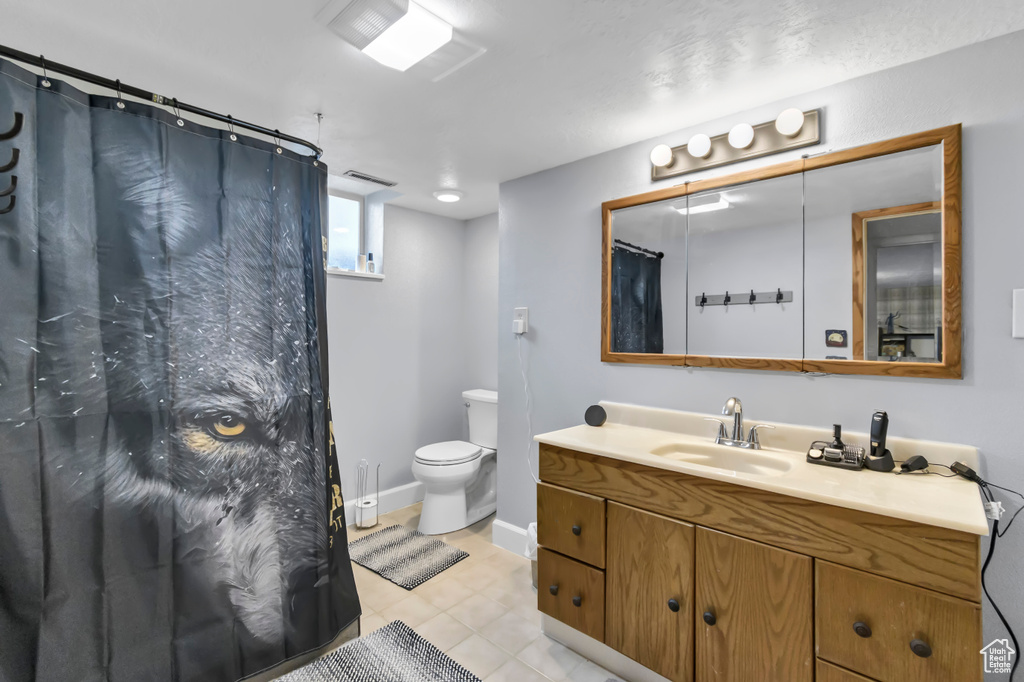 Bathroom with vanity, toilet, a shower with curtain, baseboards, and tile patterned flooring
