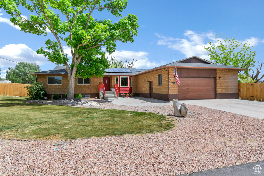 Ranch-style house with an attached garage, roof mounted solar panels, brick siding, concrete driveway, and entry steps