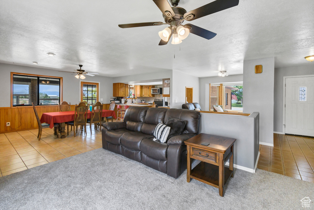 Living room with tile patterned floors, ceiling fan, carpet flooring, and baseboards