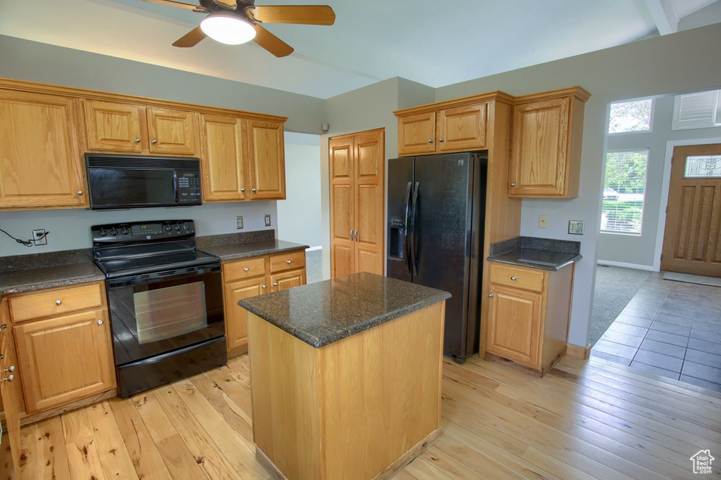 Kitchen with black appliances, ceiling fan, light wood-type flooring, and a center island