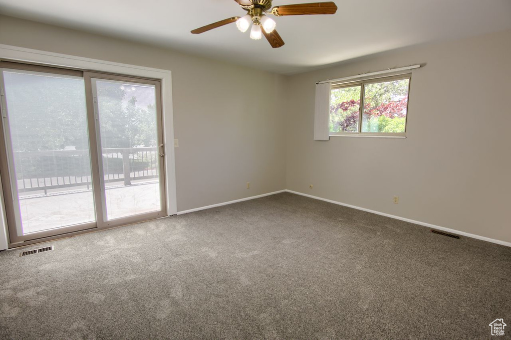 Carpeted spare room with a ceiling fan and baseboards