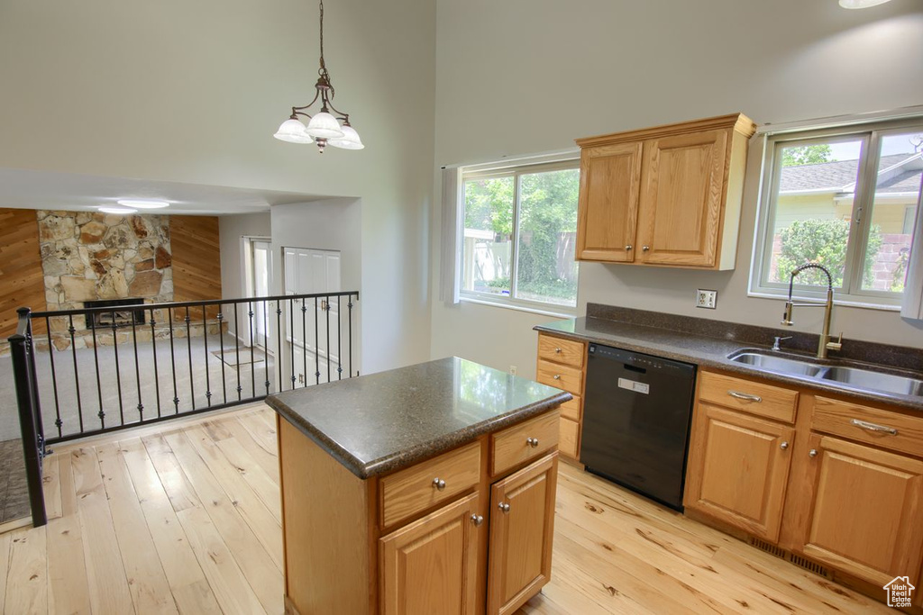 Kitchen with dishwasher, a sink, light wood-type flooring, dark countertops, and a chandelier