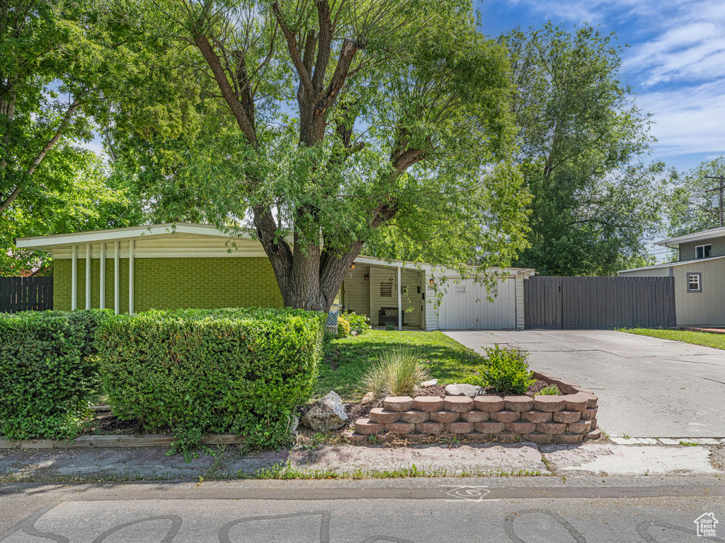 Mid-century home featuring driveway, brick siding, and a gate